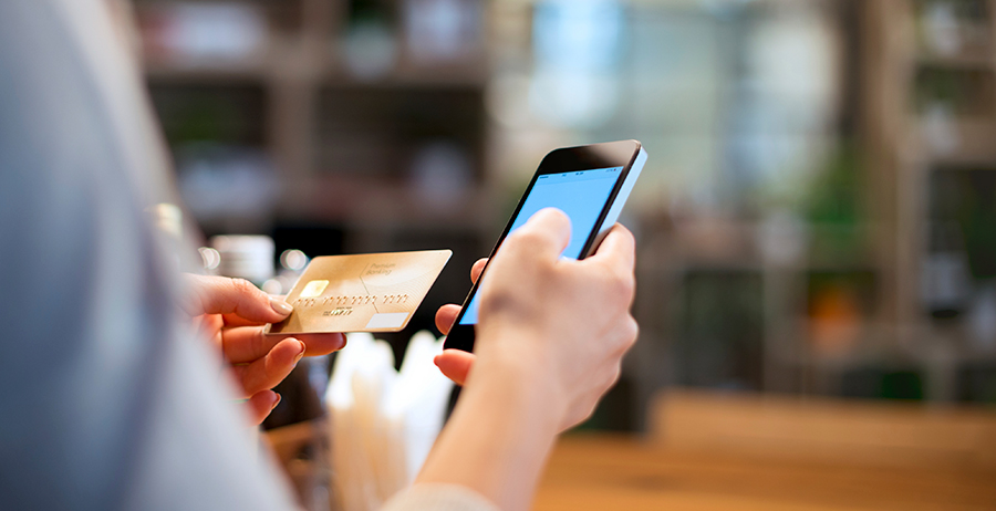 Image shows someone using their cellphone to make a card payment as part of basic finances in today’s marketplace.